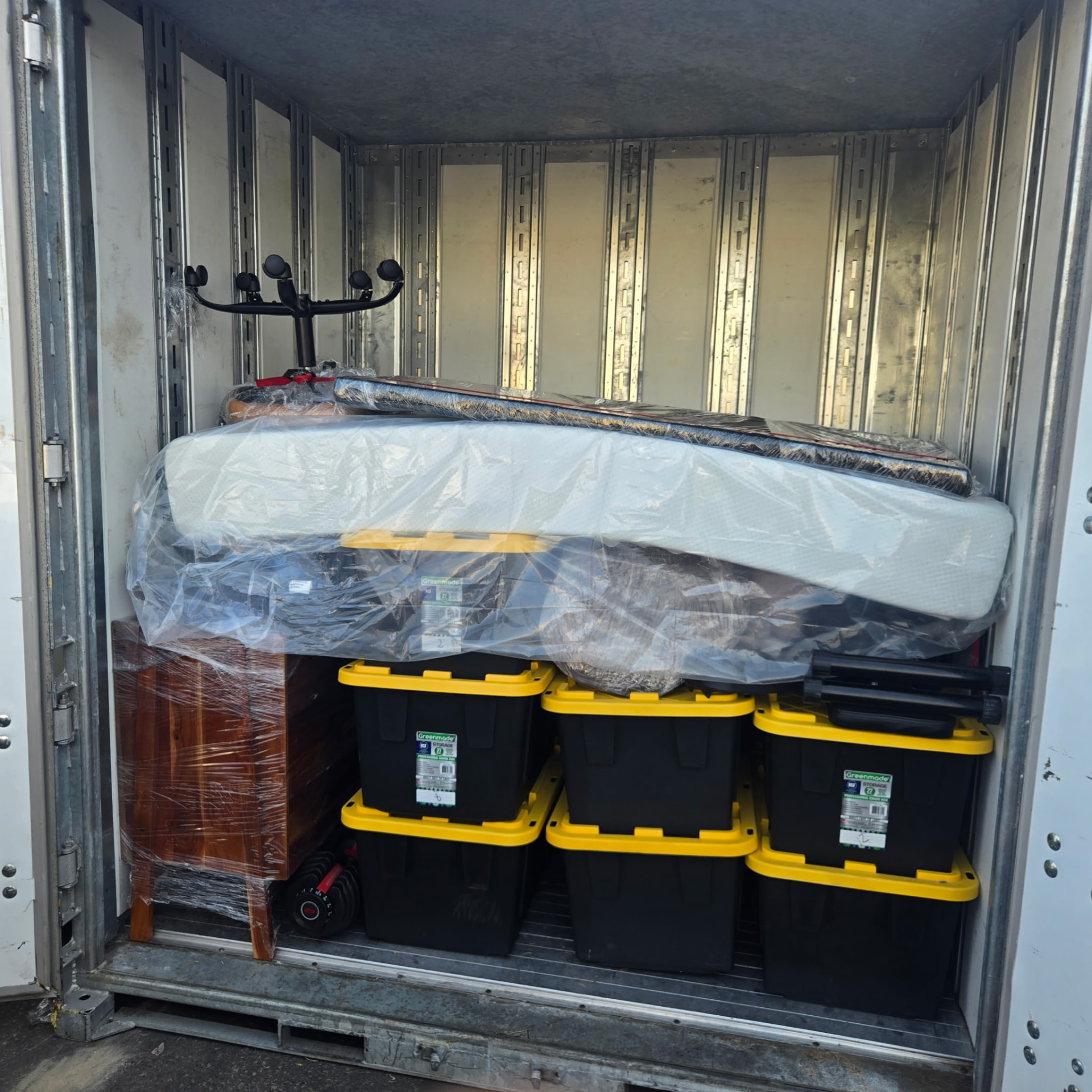 Neatly loaded trailer with wrapped mattress, furniture and storage bins
